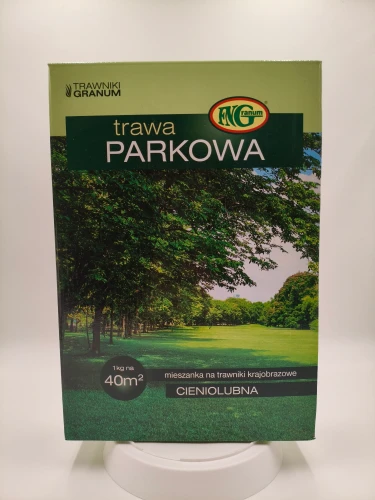 Pudełko trawy Parkowej Granum z drzewami w tle sugeruje zastosowanie w cieniu.